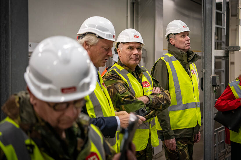 4 personen met een geel hesje en witte helm naast elkaar.