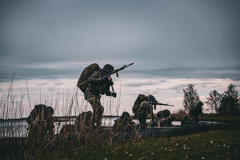 Militairen komen aan land met geweer in aanslag.