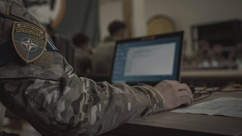 Militair met mouwembleem enhanced Forward Presence achter computer.