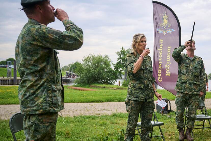 De koningin drinkt een borrel mee met militairen.
