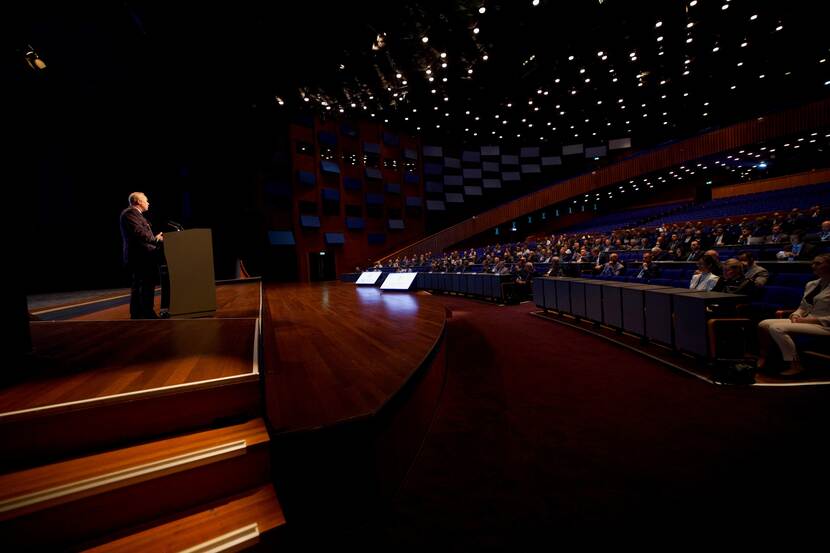 Een speechende commandant der strijdkrachten voor een volle zaal.
