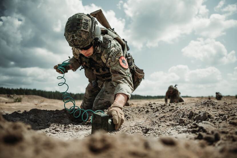 Militair plaatst explosief onder dik pakket grijze wolken.