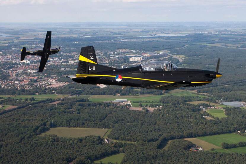 2 PC-7 Turbo Trainers vliegen boven land.