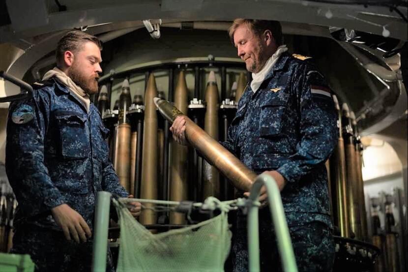 De koning houdt een munitiestuk vast op de Zr Ms Van Amstel