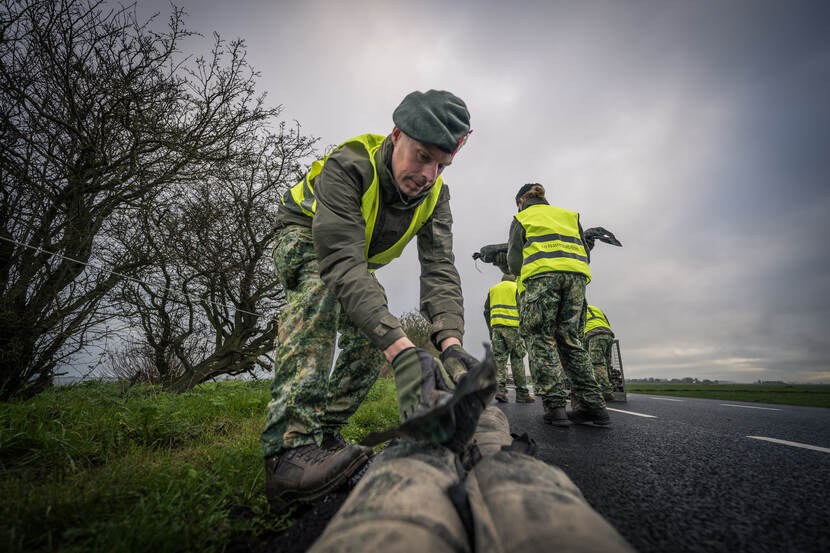 Een militair legt zandzakken neer