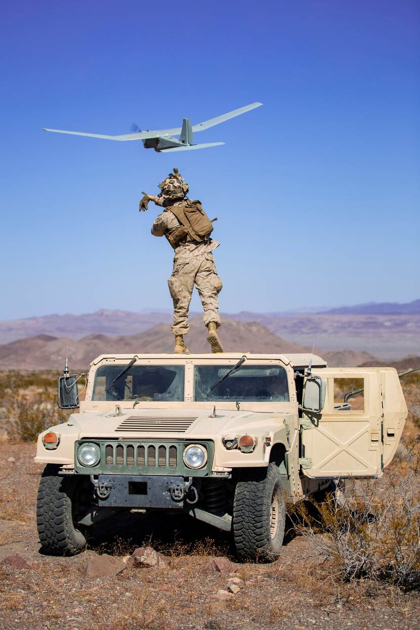 Militair op dak van jeep gooit drone in de lucht