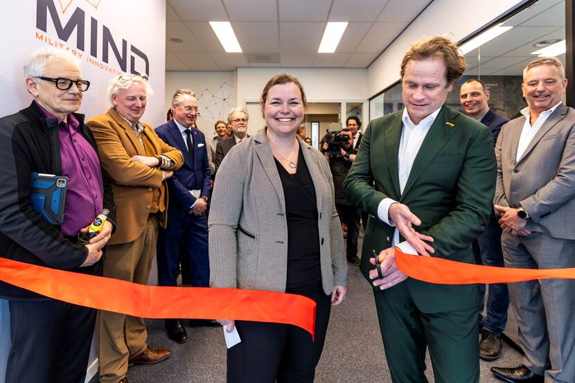 Gijs Tuinman knipt oranje lint door.  Een vrouw naast hem. Mensen langs de zijlijn.