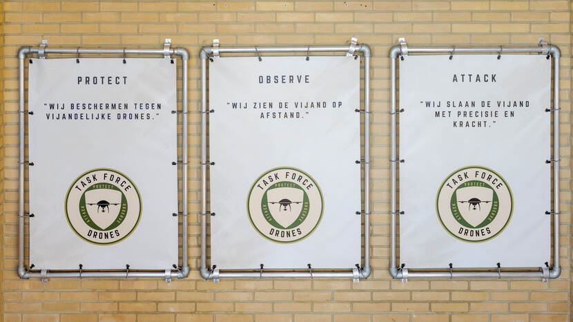 Een muur met daarop 3 afbeeldingen van de Task Force Drones.