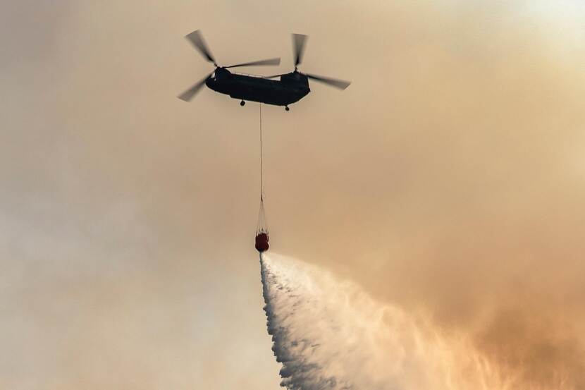 Defensie zet een Chinook-transporthelikopter in om te helpen bij brandbestrijding.