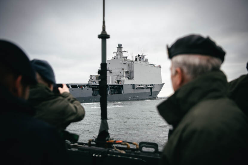 Militairen kijken vanaf een schip naar een ander schip.