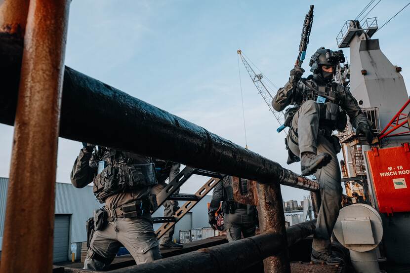 Militair springt over een hekje.