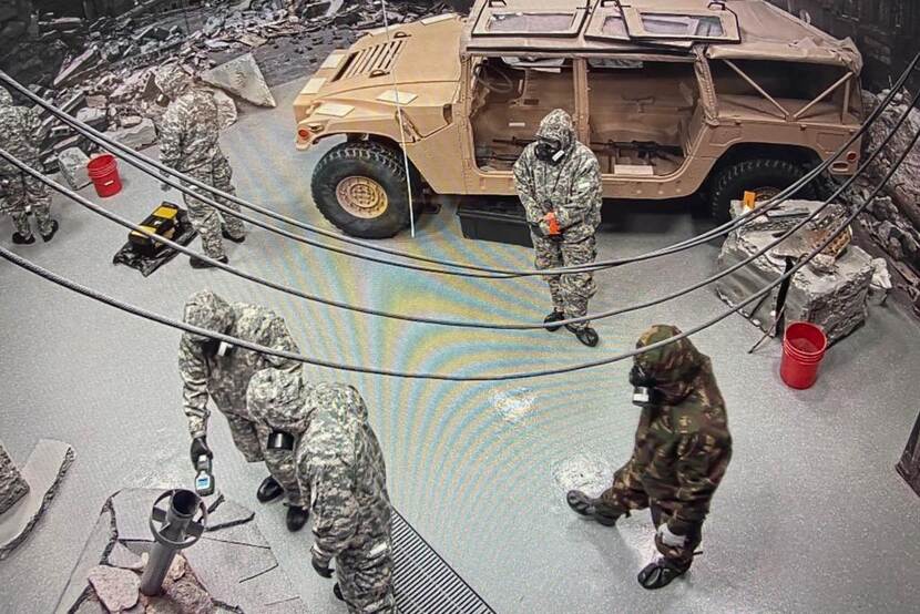 Militairen in beschermende pakken in oefenruimte met gevaarlijke stoffen.