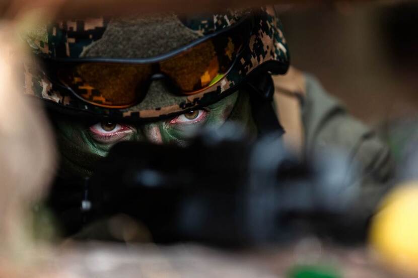 Militair met helm en gecamoufleerd gezicht. Alleen de ogen zijn zichtbaar.