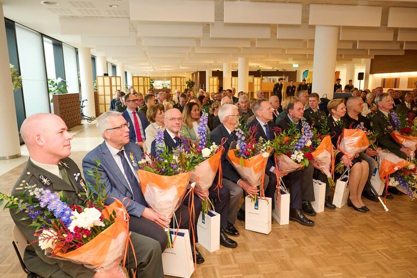 Mensen op eerste rij. Allen met een boeket bloemen in handen.