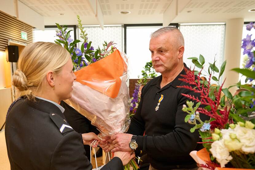 Bloemen voor gedecoreerde Ton Monster. Vrouwelijke militair reikt het boeket uit.