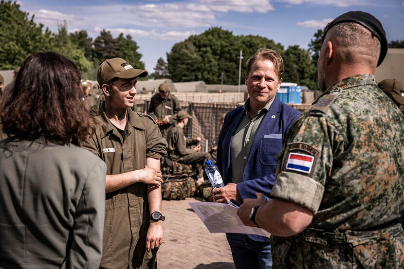 Staatssecretaris Gijs Tuinman praat met militair en twee jongeren.