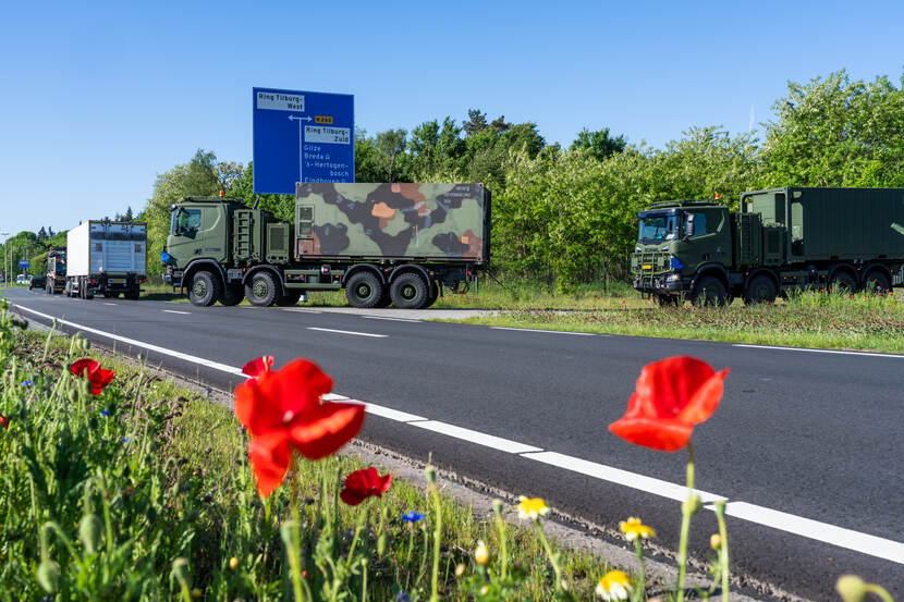 Militaire vrachtwagens rijden de weg op.