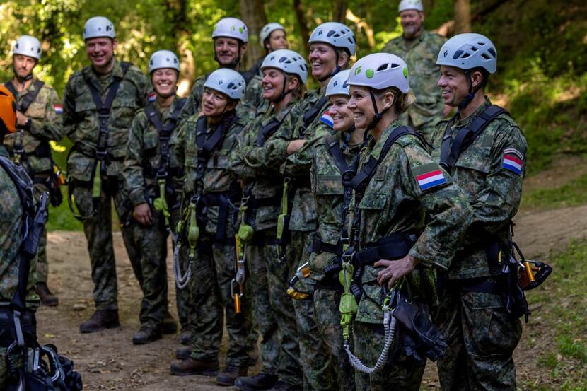 Koningin Maxima in militair uniform en witte helm staat in groep militairen met witte helm.