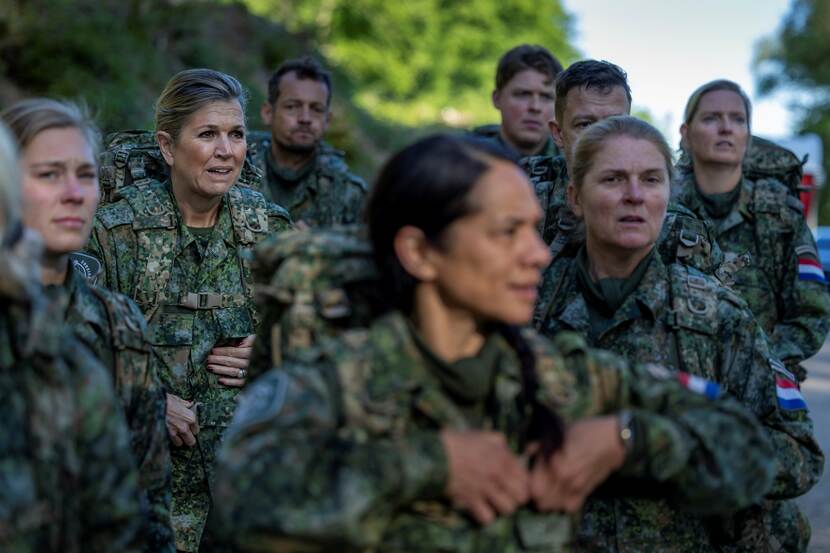 Koningin Maxima in uniform en rugzak loopt tussen groep militairen.