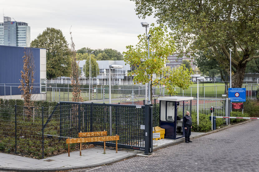 Een beveiliger staat voor de poort van het Marine Etablissement Amsterdam.