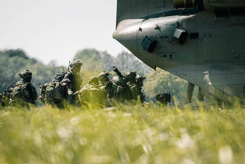 Militairen naast een helikopter.
