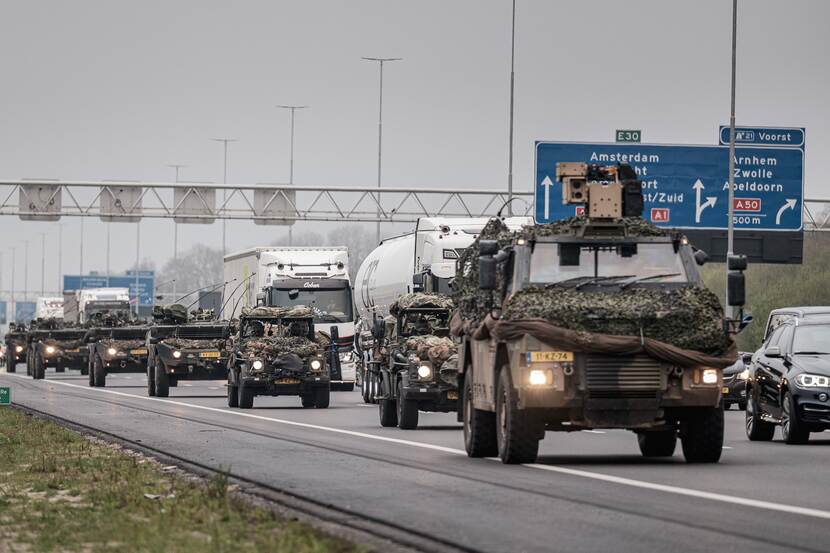 Een rij militaire voertuigen op de snelweg.