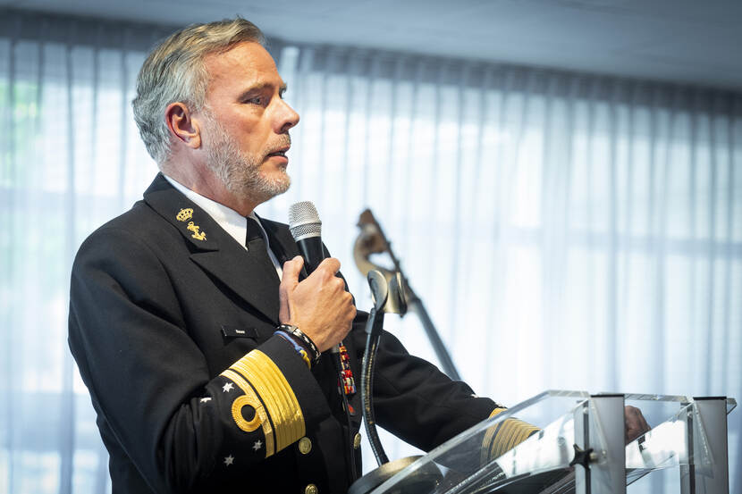 Bauer spreekt vanachter katheder in microfoon.