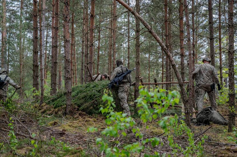 Militairen bij schuilplaats in bos.