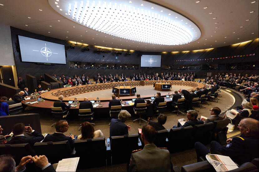 NAVO-ministers zitten aan grote ovale vergadertafel.