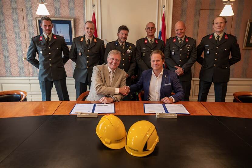 Staatssecretaris Gijs Tuinman geeft Heijmans een hand nadat ze de overeenkomst hebben getekend.