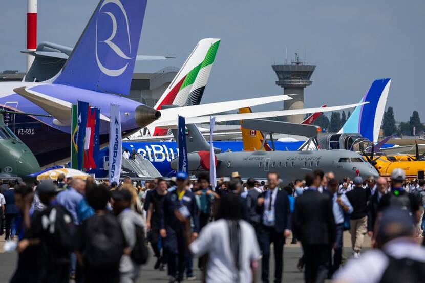Drukte op het buitenterrein van de Paris Air Show. Op de achtergrond een vliegtuig.