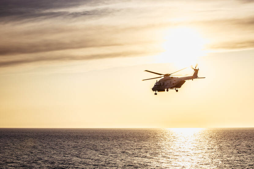 Een helikopter vliegt boven zee.