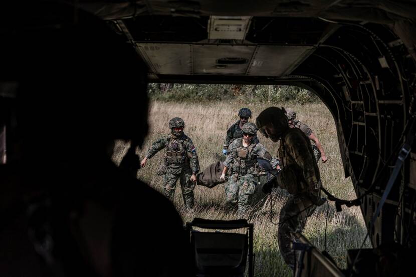Militairen dragen gewonde op draagbaar militaire ambulance in.