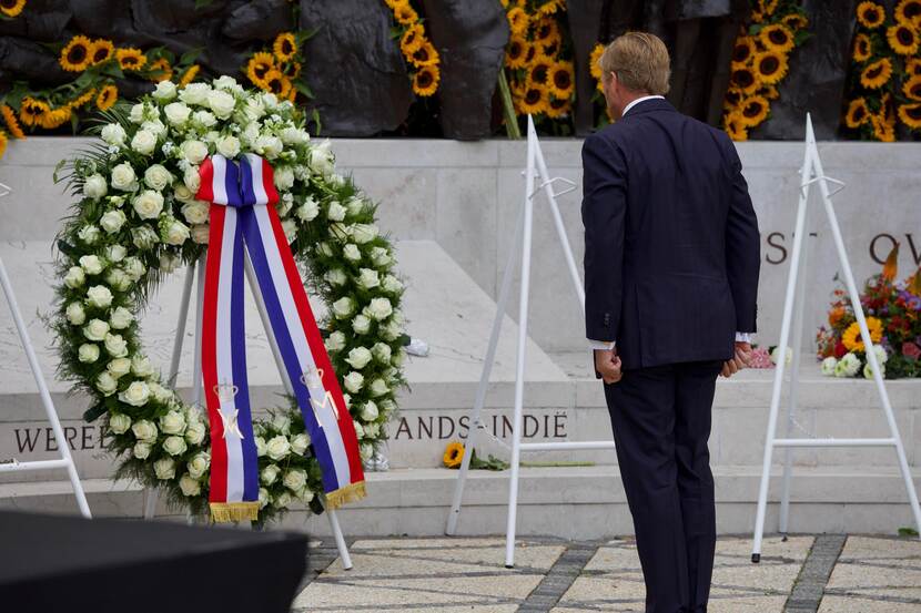 De Koning staat voor de krans bij het monument.