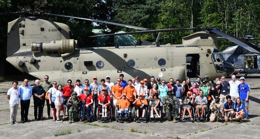 Een groep jongeren staat voor een Chinook-transporthelikopter.