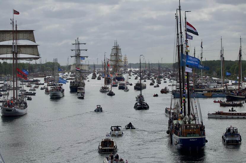 Grote hoeveelheid kleine boten en grote (zeil)schepen op het water.