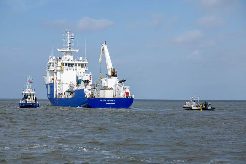 MV Geosea, van onder blauw en van boven wit, vaart op de zee en links en rechts 2 kleine bootjes erbij.