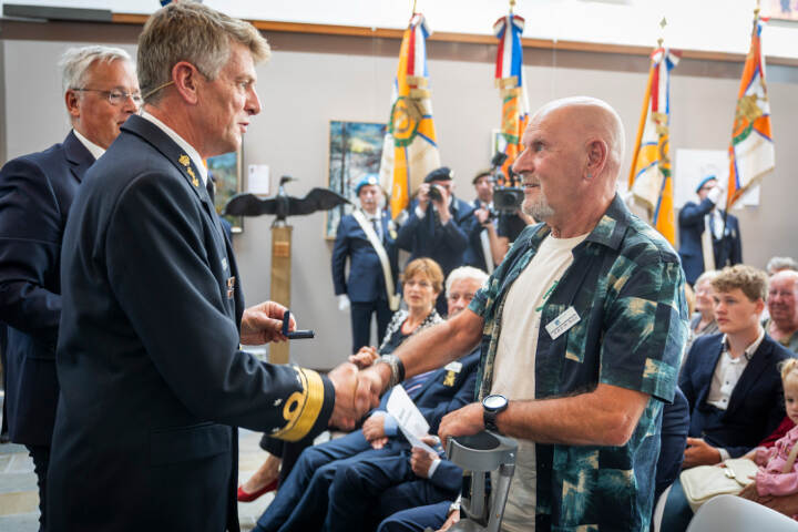 Boots reikt het insigne uit aan een man met een kruk.