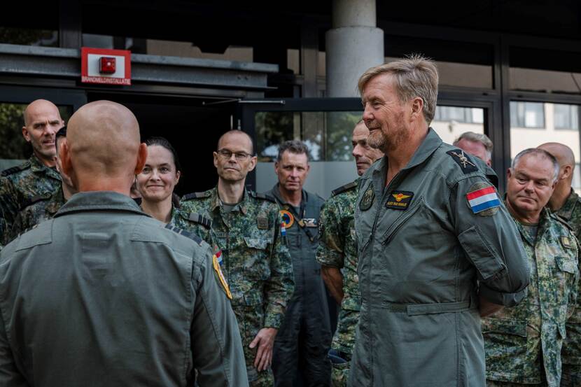 Koning Willem-Alexander in luchtmacht-overall in gesprek met militairen.