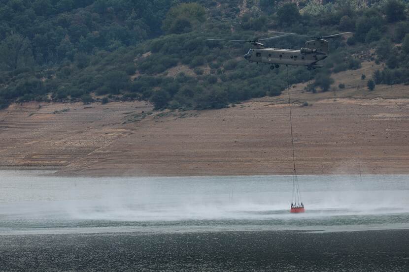 Chinook-transporthelikopter met bambi bucket boven water.
