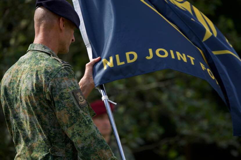 Een militair houdt de vlag van JFC vast.