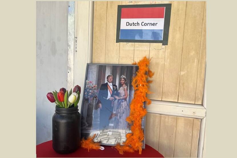 Foto van de koning en de koningin met een vaas tulpen, met daarboven een bordje met: Dutch Corner op een tafeltje in Irak