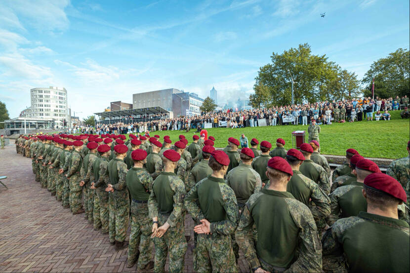 Militairen met rode baretten op staan in het gelid tijdens ceremonie.