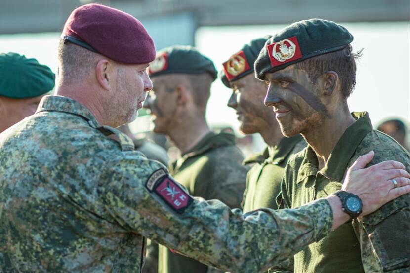 Hoge militair legt hand op schouder andere militair ter felicitatie bij ceremonie.