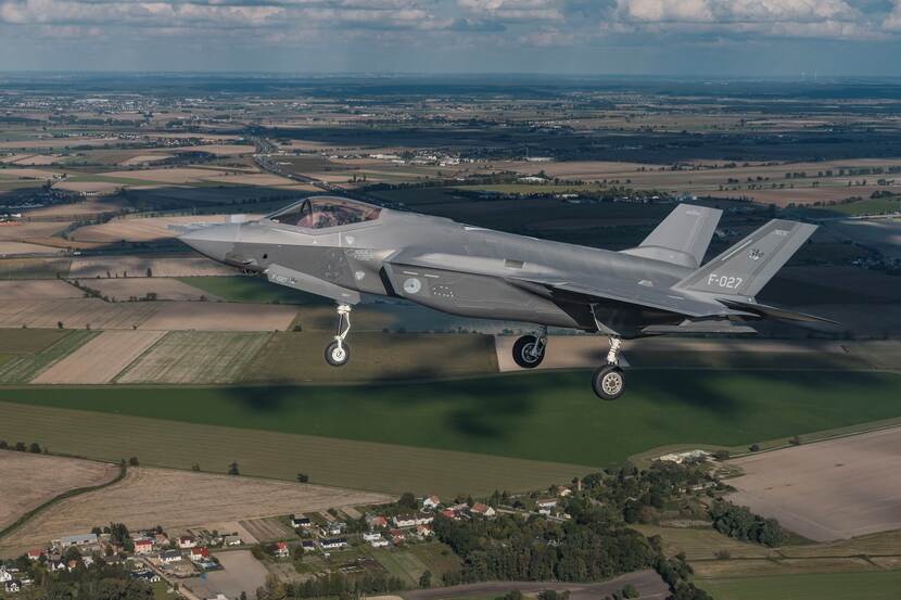 F-35 vliegt boven groen geschakeerd landschap.