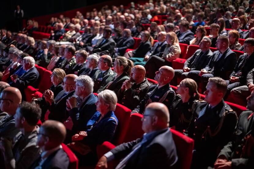 Volle theaterzaal waaronder een lange rij met militairen.