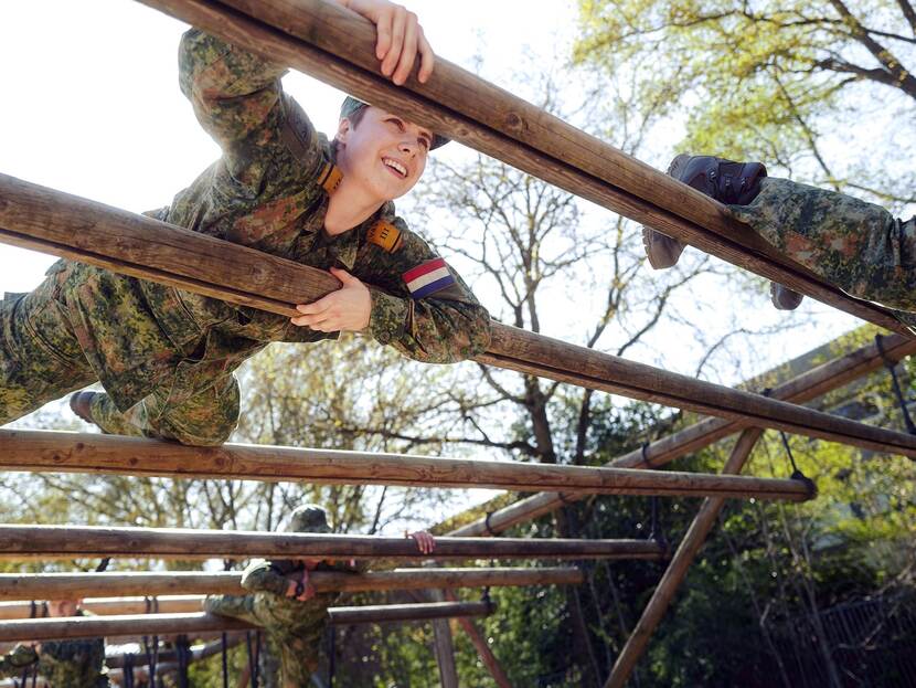 Militairen kruipen over een hindernisbaan.