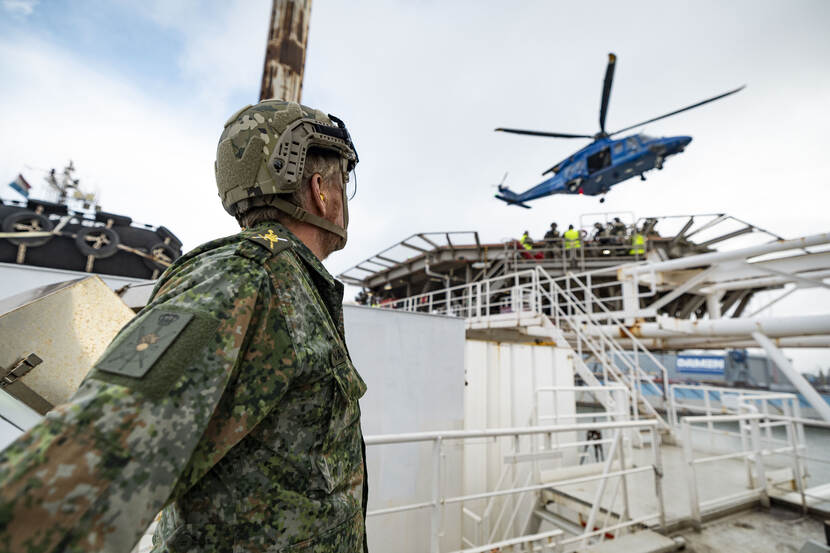 De Koning kijkt naar een helikopter in de lucht.