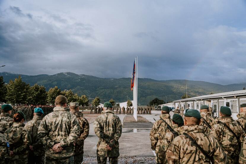 In carré aangetreden militairen. Bergen en bewolkte lucht op de achtergrond.