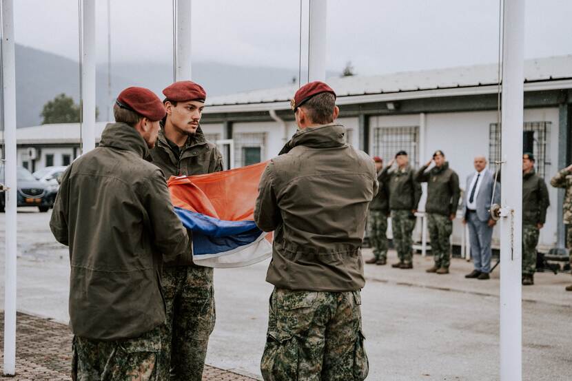 3 militairen vouwen Nederlandse vlag uit.